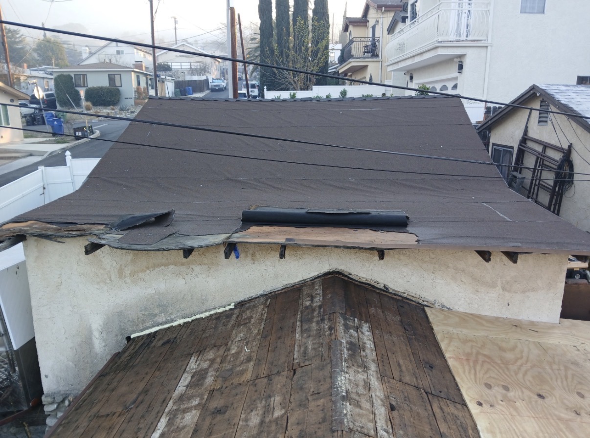 Damaged roof torn open showing rotted decking